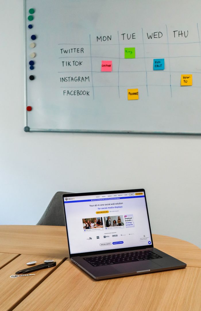 Un environnement de bureau moderne avec un ordinateur portable et un planning sur tableau blanc pour les plateformes de réseaux sociaux.